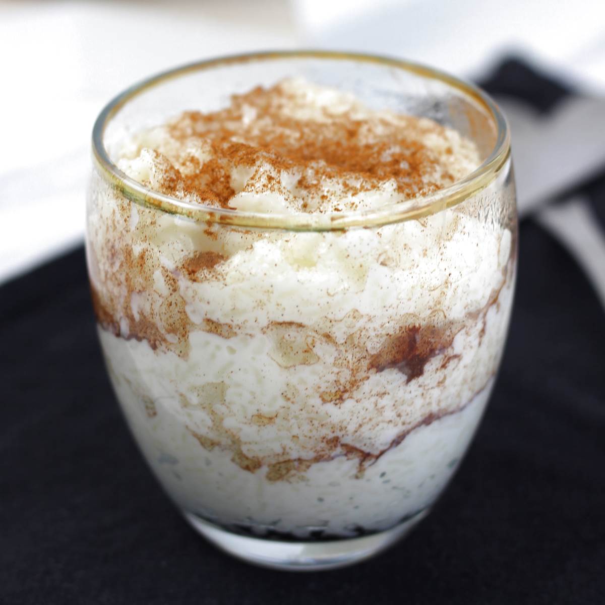 Creamy rice pudding in a glass, topped with cinnamon, perfect dessert presentation.