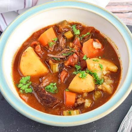 Hearty beef stew with potatoes, carrots, and parsley in a bowl, perfect for a comforting meal.