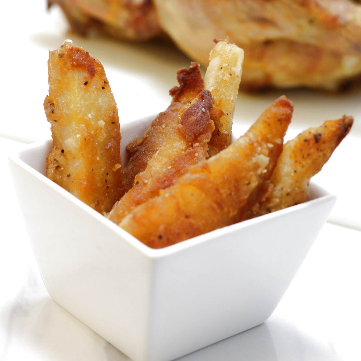 Crispy golden french fries in a white dish, perfect side for any meal.