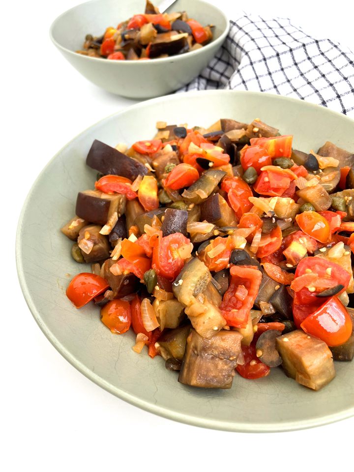 Vegetable caponata with eggplant, tomatoes, and onions in a bowl, paired with a checkered napkin. Easy Sicilian Aubergine Caponata