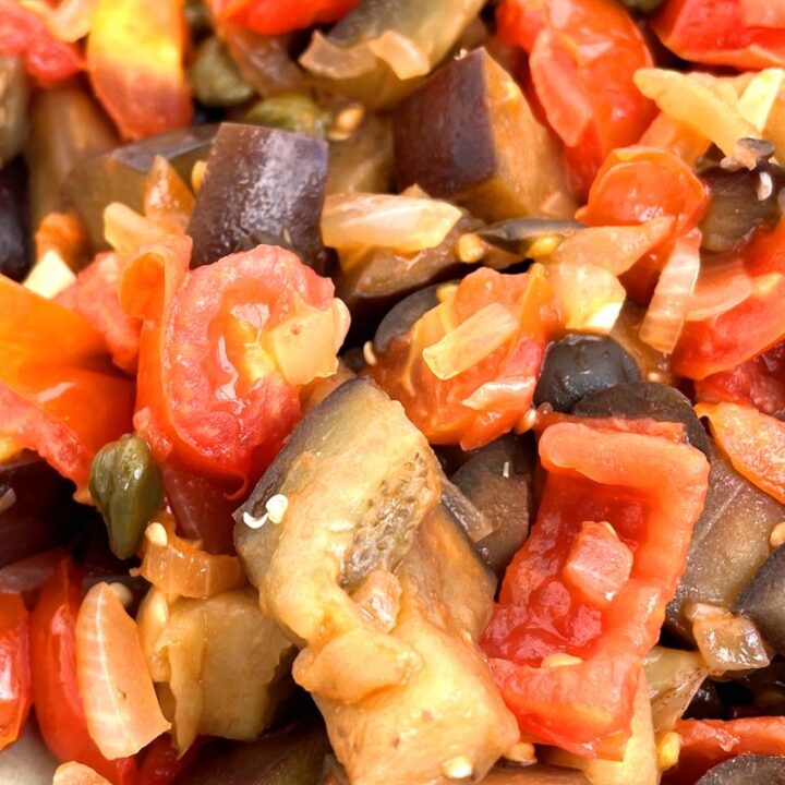 Close-up of vibrant Sicilian caponata with eggplant, tomatoes, onions, and capers, perfect for Italian cuisine lovers.