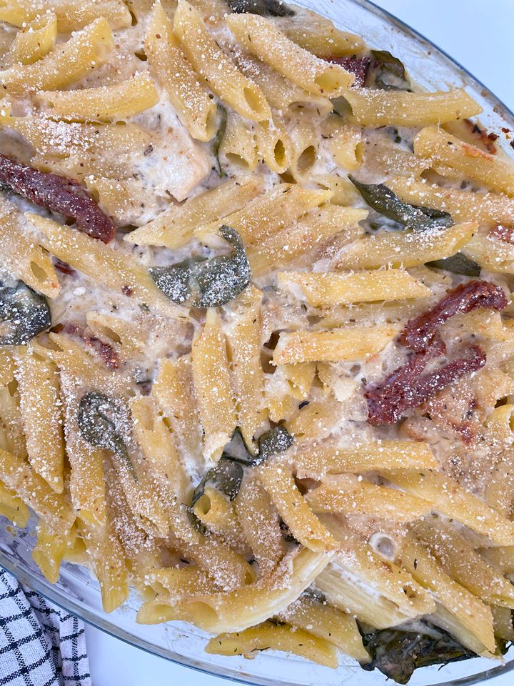 Creamy baked penne pasta with sun-dried tomatoes, fresh spinach, and a sprinkle of parmesan cheese on top.