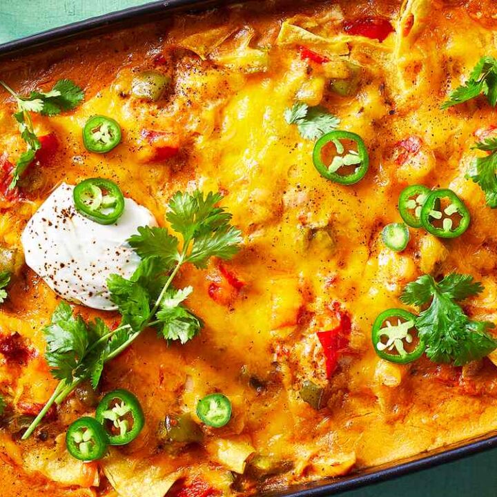 Delicious chicken enchilada casserole topped with cheese, jalapeños, and sour cream in a baking dish.
