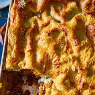 Golden-baked lasagna in a pan on a blue tablecloth, perfect for a cozy dinner.