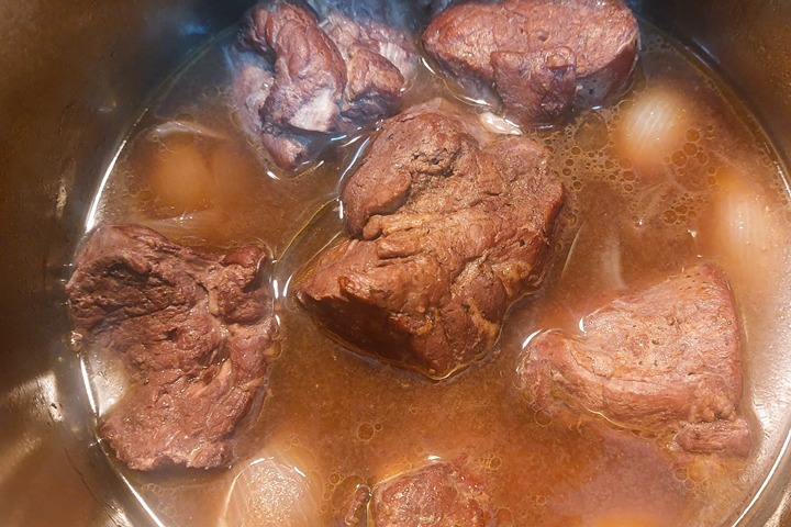 Tender pork pieces simmering in rich broth in a pot, ideal for a hearty stew recipe or slow-cooked meal.