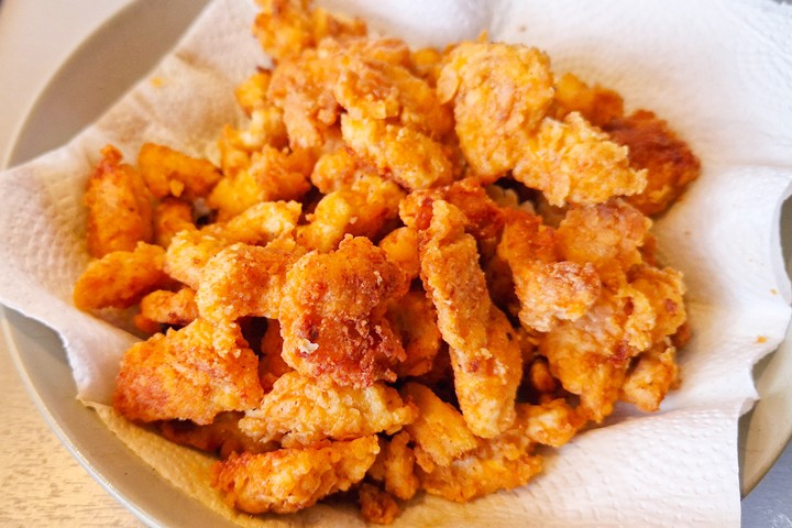 Crispy, golden-brown fried chicken pieces piled on a plate, garnished with paper towels for a delicious serve.