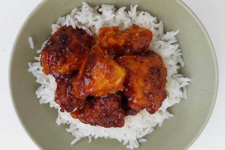 Spicy barbecue chicken served on fluffy white rice in a bowl.