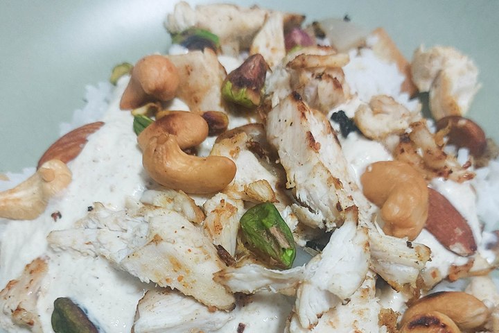 Delicious grilled chicken with cashews and pistachios on rice, topped with creamy sauce. Healthy and nutty dish.