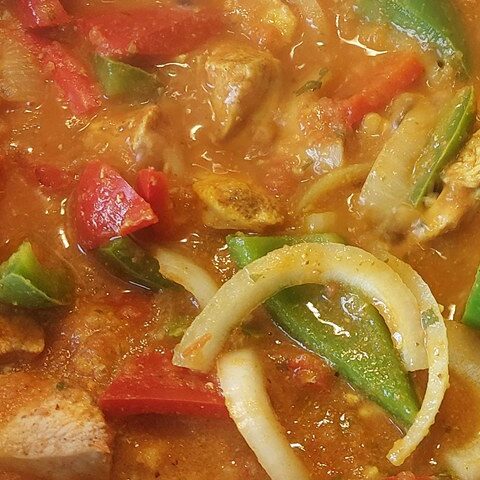 Delicious chicken stew with colorful bell peppers and onions simmering in a rich, flavorful sauce.