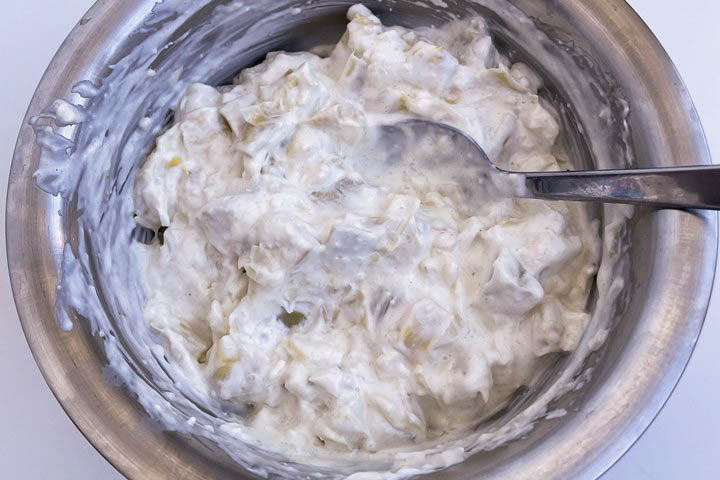 Creamy yogurt-based salad mixture in a stainless steel bowl, ready to serve or use as a topping.