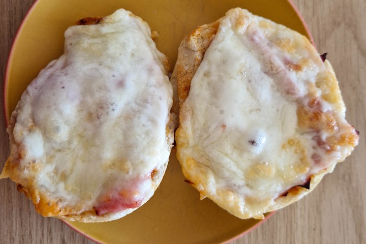 Two deliciously melted cheese and ham sandwich halves on a yellow plate, showcasing golden crispy edges.