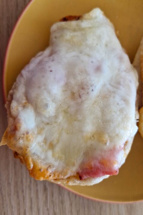 Cheesy bread topped with melted cheese on a yellow plate, perfect for a delicious snack or appetizer.