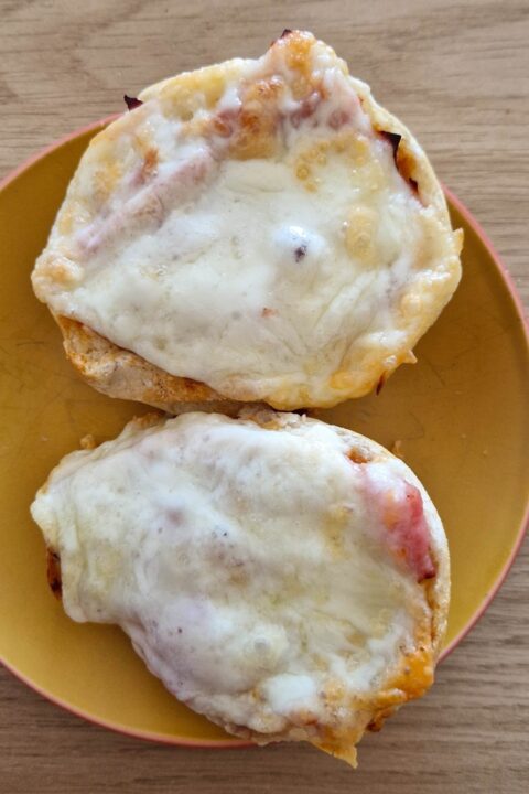 Melted cheese and ham on toasted bread slices served on a yellow plate, perfect for a delicious snack or breakfast.
