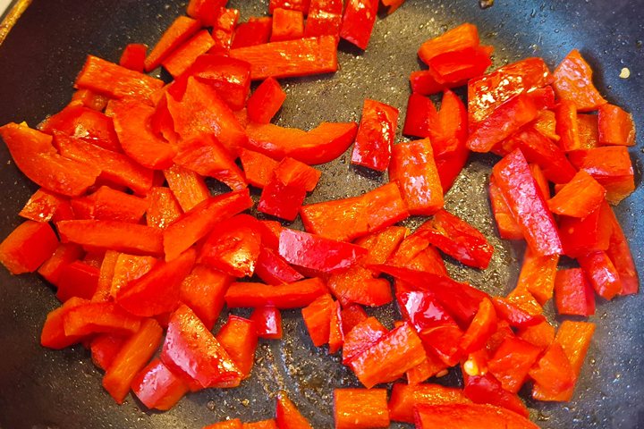 Sautéed red bell peppers in a frying pan, showcasing vibrant colors and texture for healthy cooking.