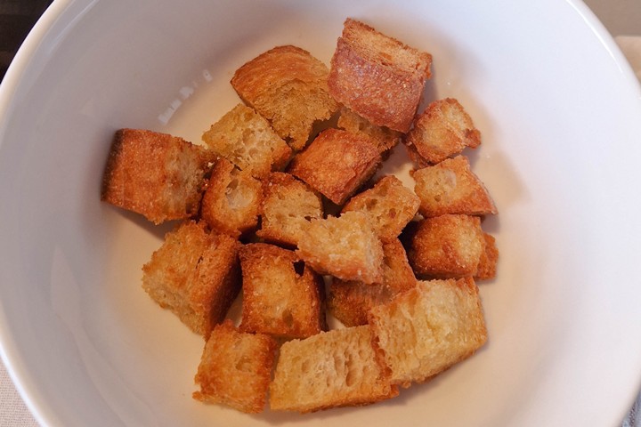Golden brown homemade croutons in airfryer in a white bowl, perfect for adding crunch to salads and soups.