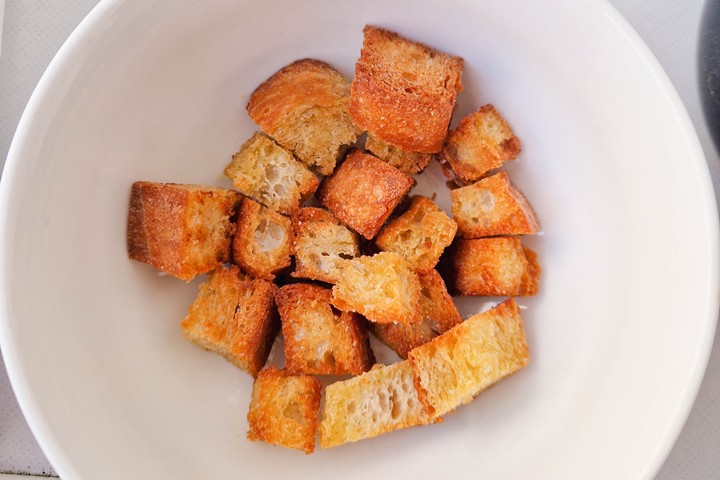 Golden-brown croutons arranged in a bowl, perfect for adding crunch to salads or soups.